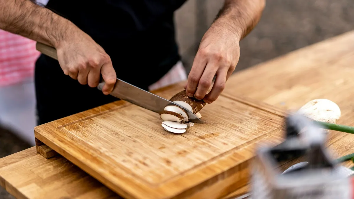 Chef slicing food with a kitchen knife on a cutting board