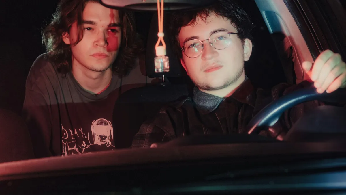 Two young men sitting in a car at night
