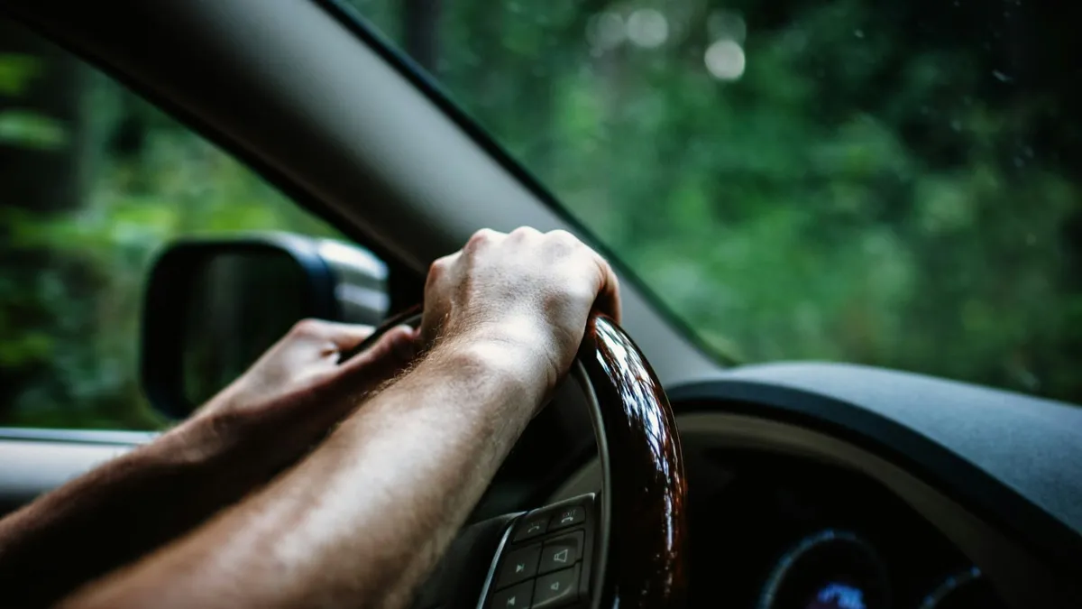 Driver's hands on the steering wheel of a car