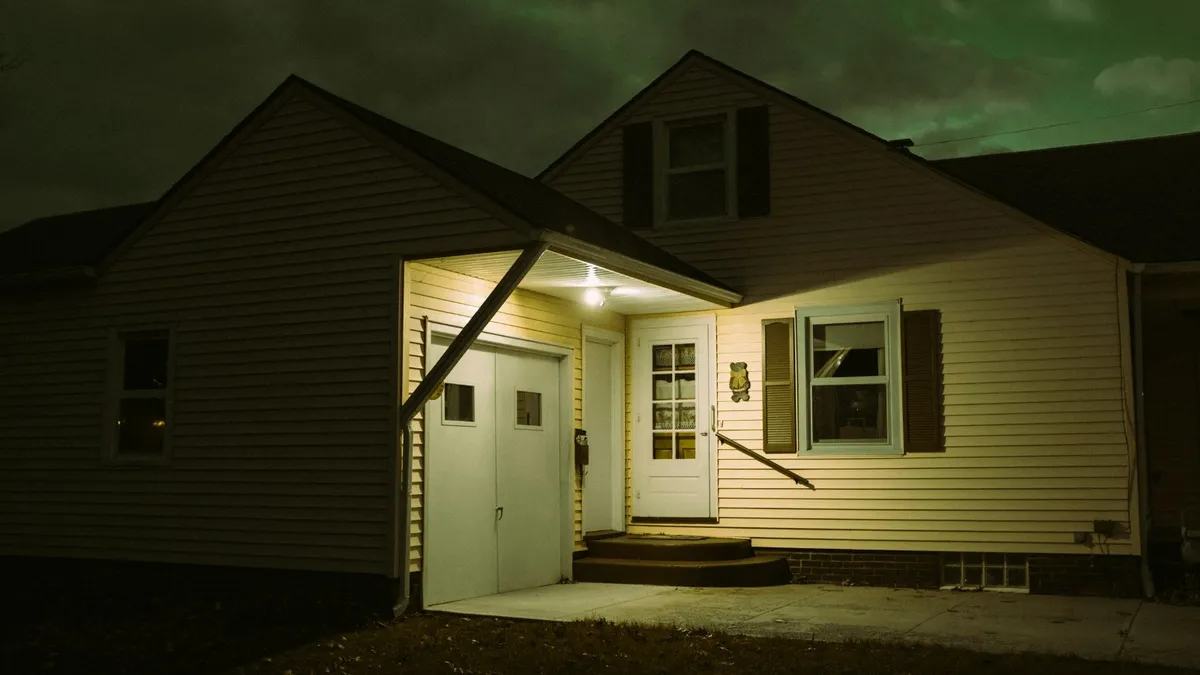 Front of a suburban house at night with the porch light on